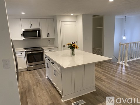 A kitchen with white cabinets and a wooden floor.
