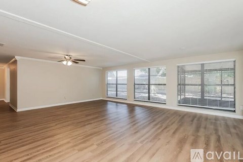 A spacious room with wooden flooring and a ceiling fan.