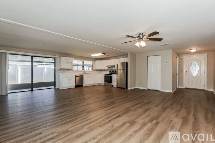 A spacious room with wooden flooring and a ceiling fan.