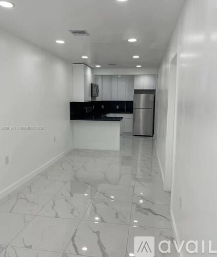 A kitchen with white marble flooring and a black countertop.