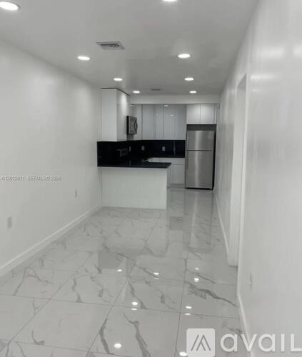 A kitchen with white marble flooring and a black countertop.