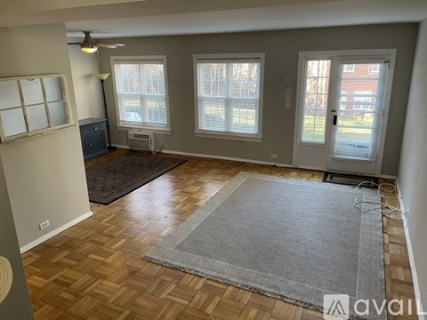 A room with wooden flooring and a grey rug in the foreground.