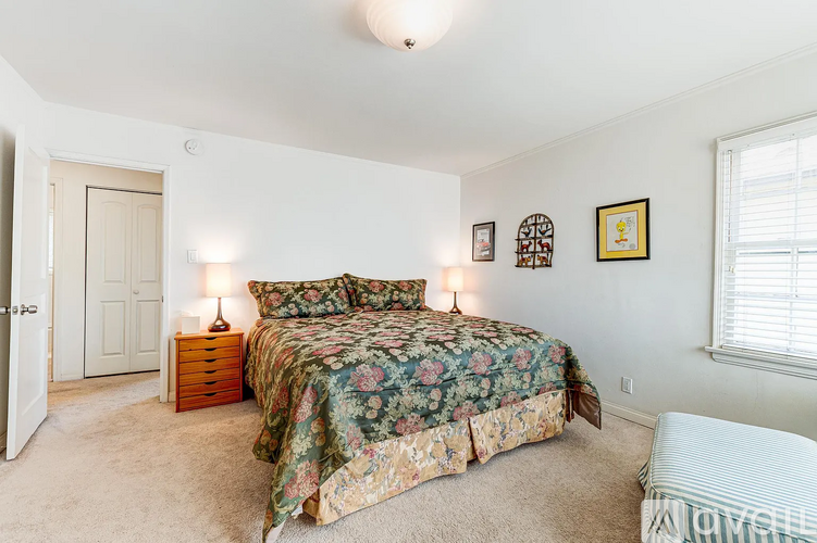 A bedroom with a floral bedspread and two lamps on bedside tables.