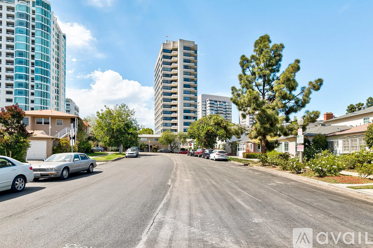 A street view with cars parked on the side and buildings in the background.