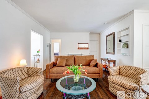 A living room with a brown sofa and a glass coffee table.