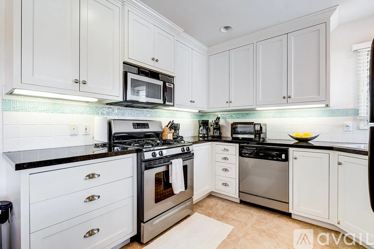 A kitchen with white cabinets and black countertops.