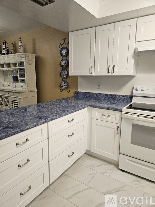 A kitchen with white cabinets and a white stove.