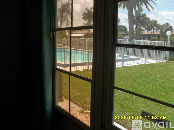 A window with a view of a pool and a fence.