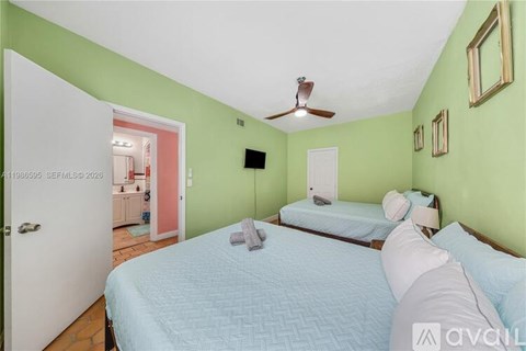 A bedroom with a bed, a ceiling fan, and a mirror on the wall.