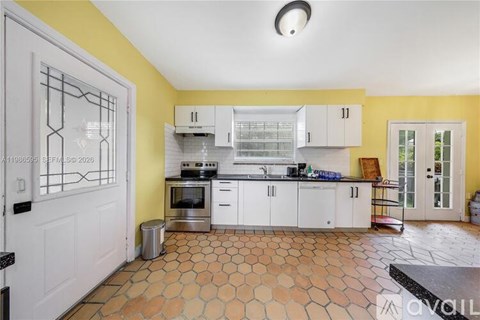 A kitchen with yellow walls and white cabinets.
