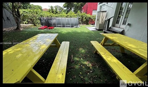 A yellow picnic table and benches are set up in a grassy area.