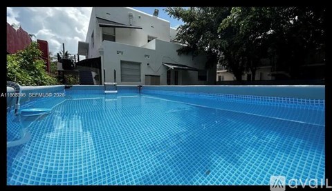 A swimming pool in front of a white building.