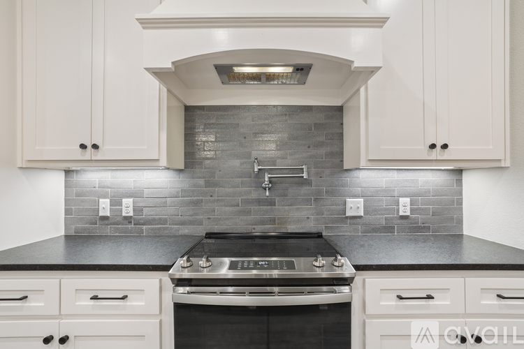 A kitchen with white cabinets and a black countertop.
