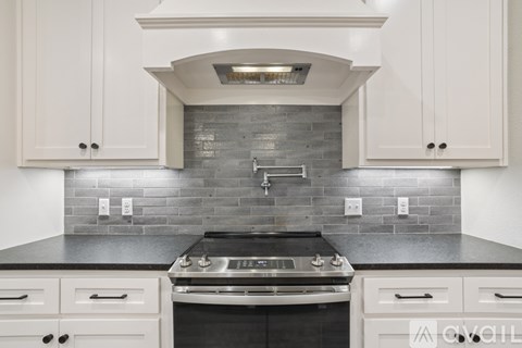 A kitchen with white cabinets and a black countertop.