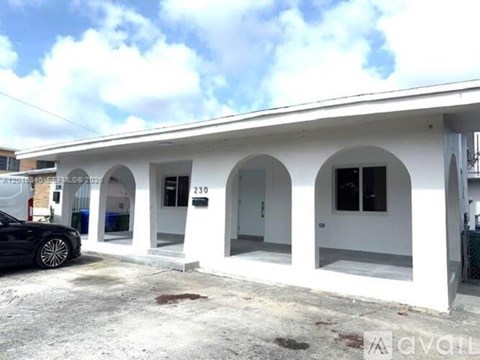 A white building with arched windows and a black car parked in front.