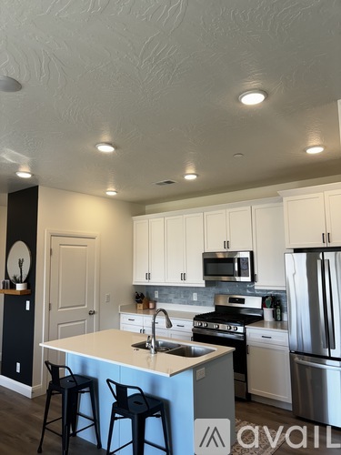 A kitchen with a white counter top and black bar stools.