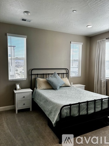 A bedroom with a bed, nightstand, and window.