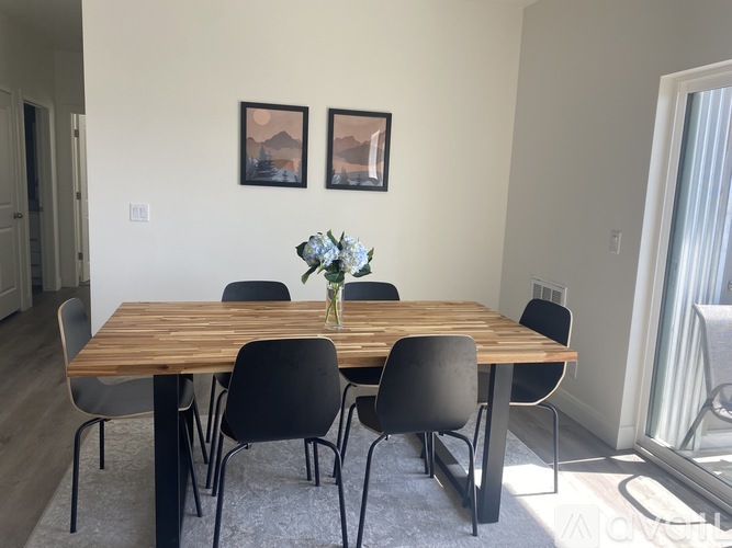 A dining table with chairs and two pictures on the wall.
