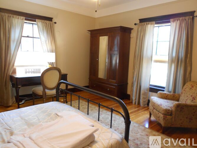 A bedroom with a bed, chair, and cabinet.