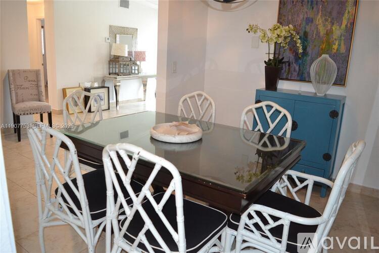 A dining room with a glass table and white chairs.