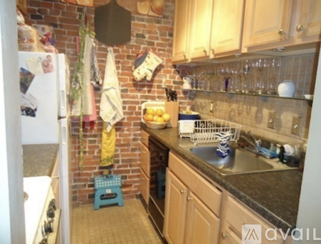 A kitchen with a brick wall and wooden cabinets.