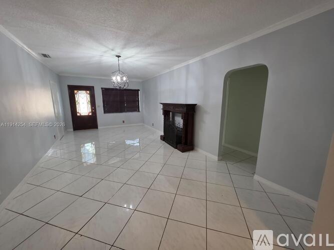 A spacious room with a fireplace and a chandelier.
