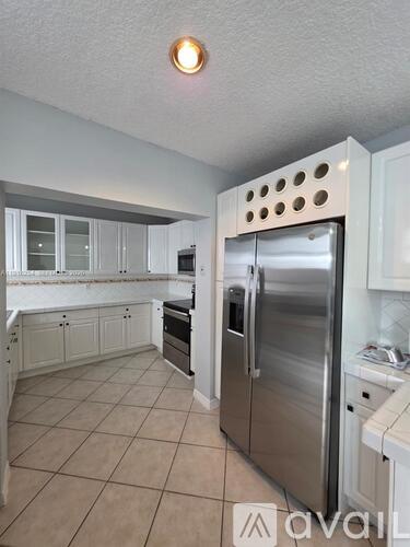 A kitchen with a stainless steel refrigerator and white cabinets.