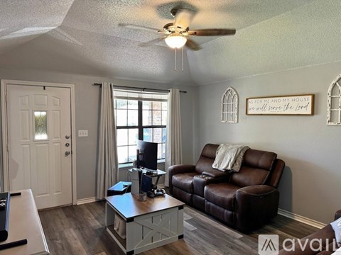 A living room with a brown leather couch and a ceiling fan.
