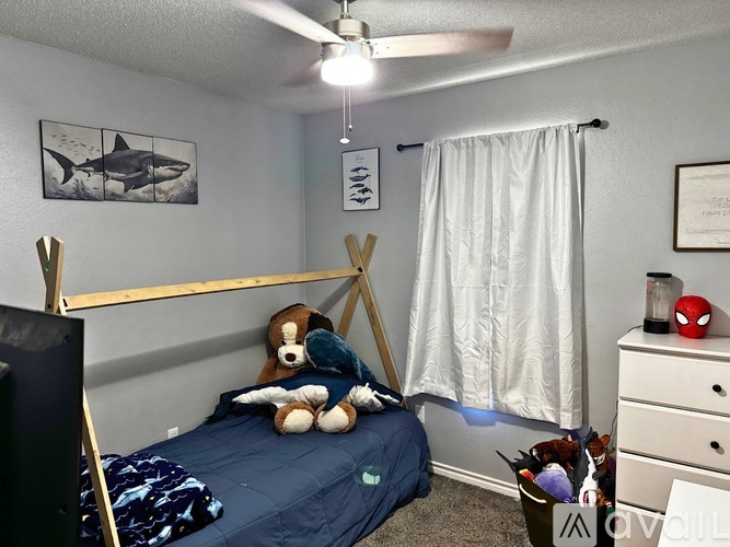 A bedroom with a bed, a teddy bear, and a ceiling fan.