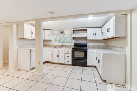 A kitchen with white cabinets and black appliances.