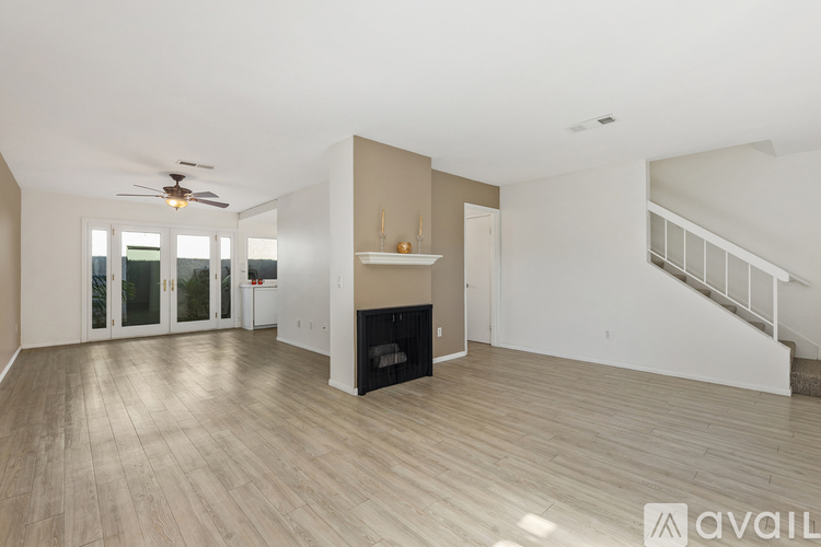 A spacious living room with a fireplace and a staircase.