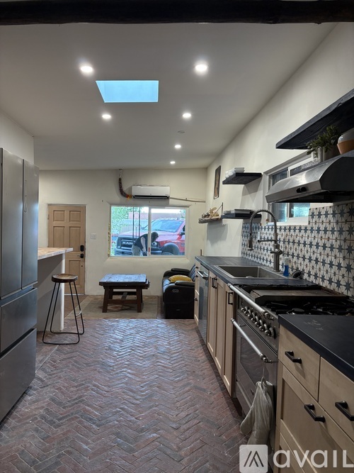A kitchen with a black counter top and a skylight.