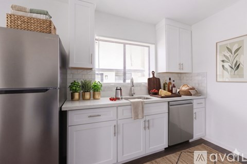 A kitchen with white cabinets and a stainless steel refrigerator.