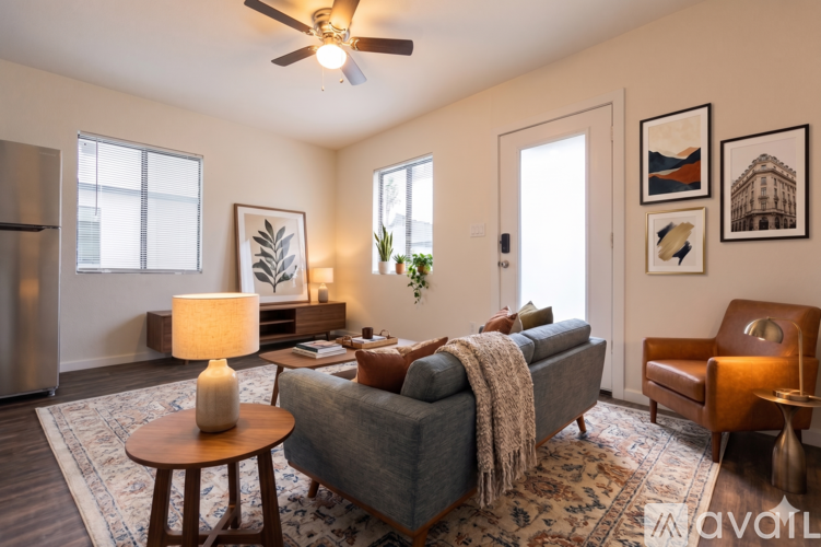 A living room with a grey couch, a wooden table, a ceiling fan, and a rug.