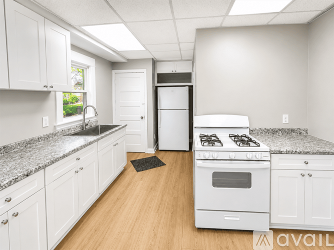 A kitchen with white cabinets and a white stove top oven.