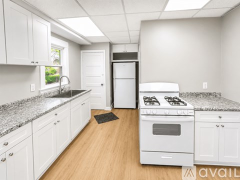 A kitchen with white cabinets and a white stove top oven.