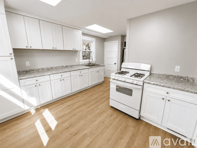 A kitchen with white cabinets and a white stove top oven.