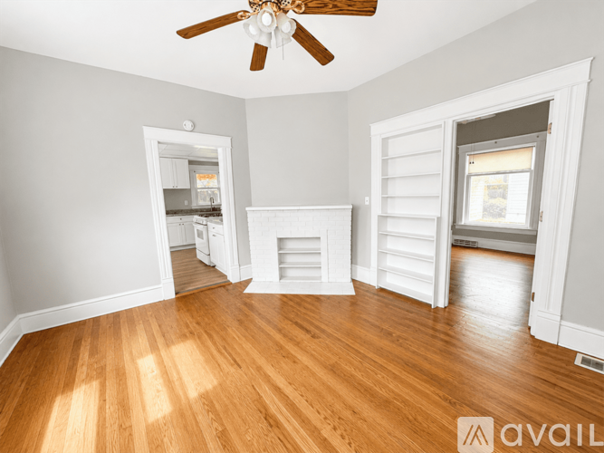 A room with a ceiling fan and wooden floors.