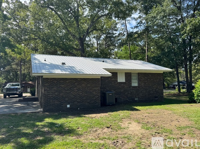 A small house with a metal roof is surrounded by trees.