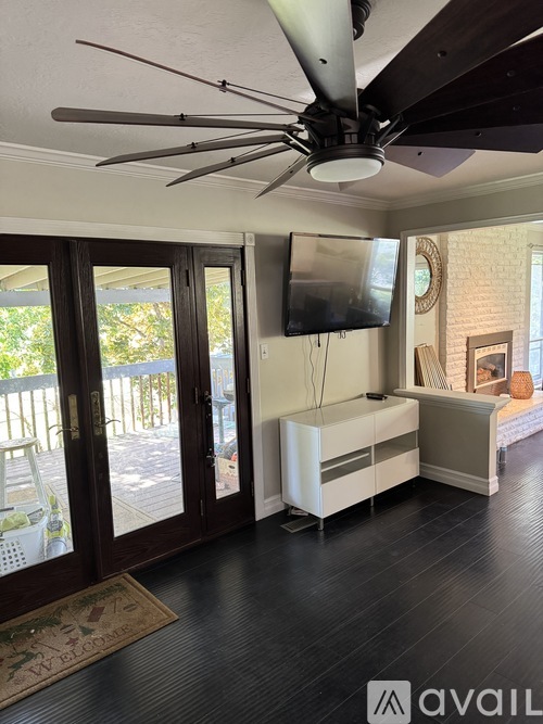 A living room with a ceiling fan and a flat screen TV mounted on the wall.
