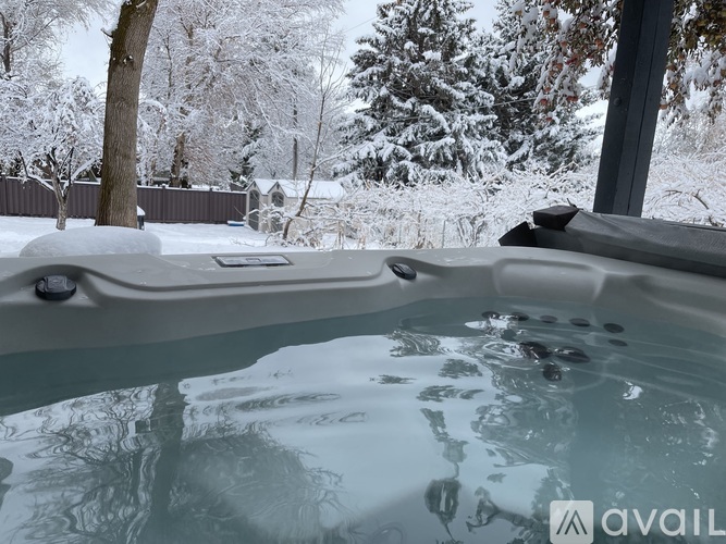 A hot tub sits in the foreground with a snowy backdrop.