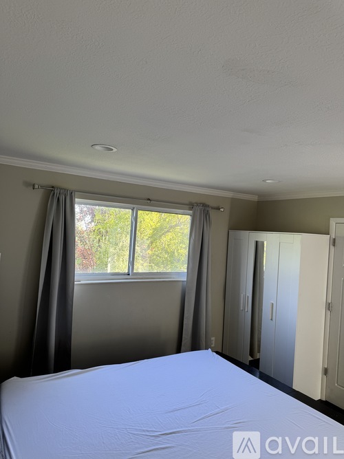 A bedroom with a large bed and a window with curtains.