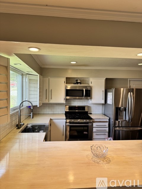 A kitchen with a wooden table in the foreground and a refrigerator to the right.