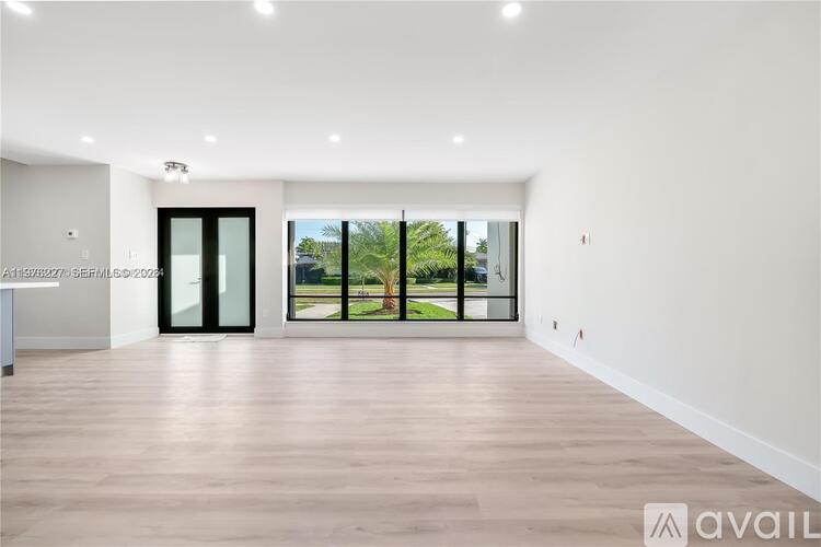 A spacious room with wooden flooring and large windows.