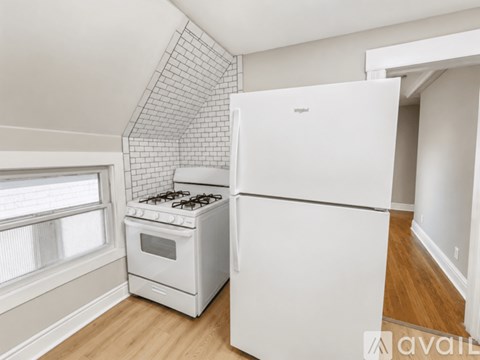 A white fridge and stove in a kitchen with a tiled wall.