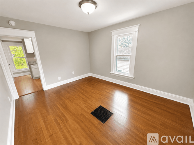 A room with wooden flooring and a window with a white frame.