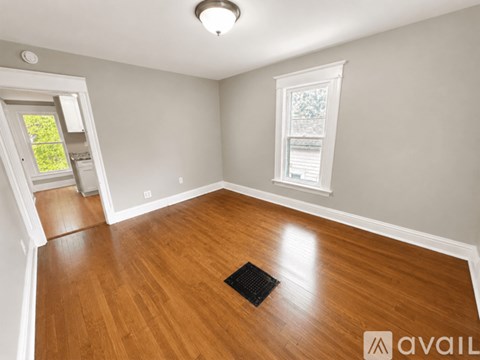 A room with wooden flooring and a window with a white frame.