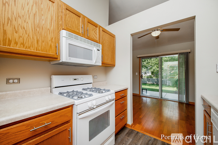 A kitchen with wooden cabinets and a white stove top oven.