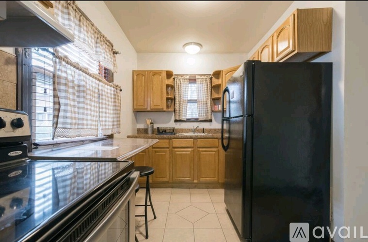 A kitchen with wooden cabinets and a black refrigerator.