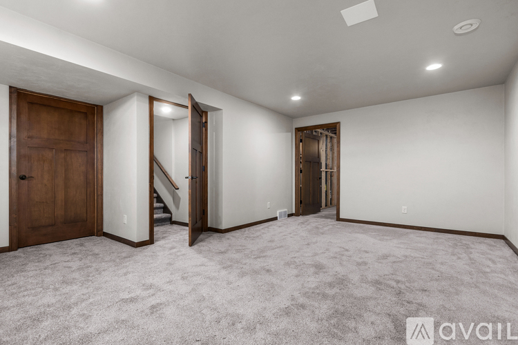 A spacious room with a carpeted floor and a staircase leading to another room.